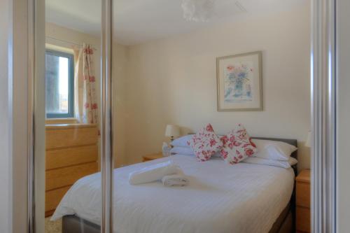 una camera da letto con un letto bianco con cuscini rossi di Harbour View a West Bay
