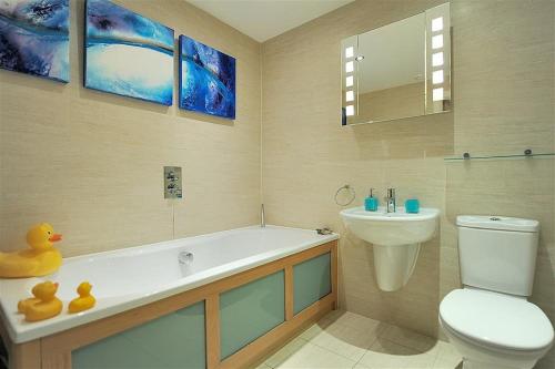 a bathroom with a tub and a toilet and a sink at Sandstones in West Bay