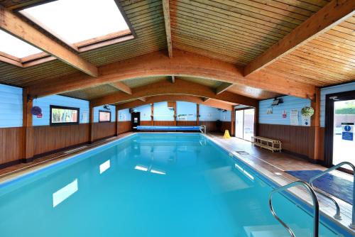 a large indoor swimming pool with a wooden ceiling at 4 Pinewood Retreat in Lyme Regis