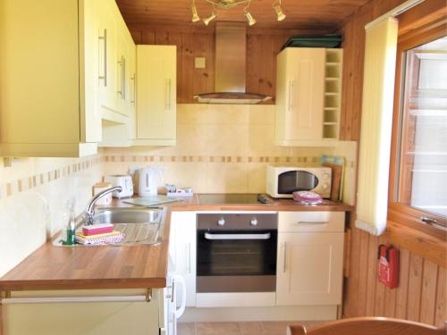 a kitchen with white cabinets and a sink at 4 Pinewood Retreat in Lyme Regis