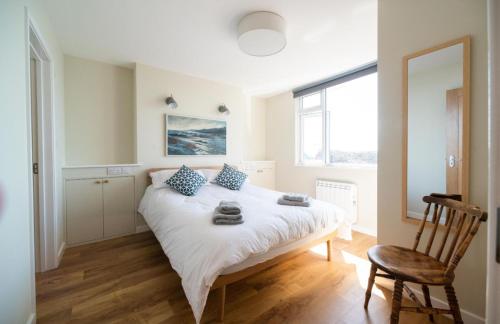 ein Schlafzimmer mit einem Bett, einem Stuhl und einem Fenster in der Unterkunft 2 Beach Way House in Lyme Regis