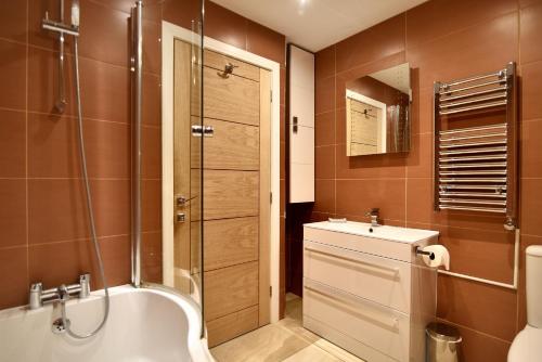 a bathroom with a tub and a sink and a shower at Pippin in Charmouth