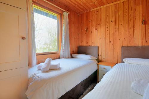 two beds in a wooden room with a window at 10 Pinewood Retreat in Lyme Regis