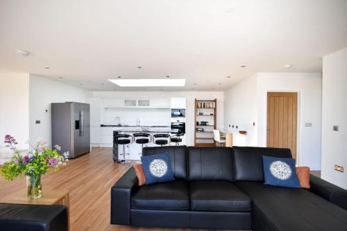 a living room with a black couch and a kitchen at Harbour Heights Cottage in Lyme Regis