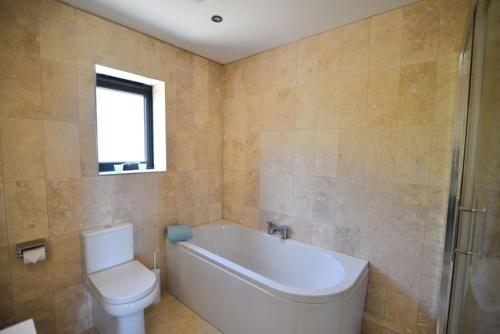 a bathroom with a white tub and a toilet at Harbour Heights Cottage in Lyme Regis
