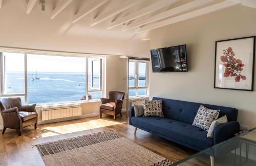 a living room with a blue couch and a large window at 3 Beach Way House in Lyme Regis