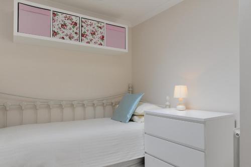 a white bedroom with a bed and a dresser at 36 Fernhill Heights in Charmouth