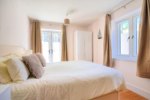 a bedroom with a white bed with a window at Seas The Day in Lyme Regis
