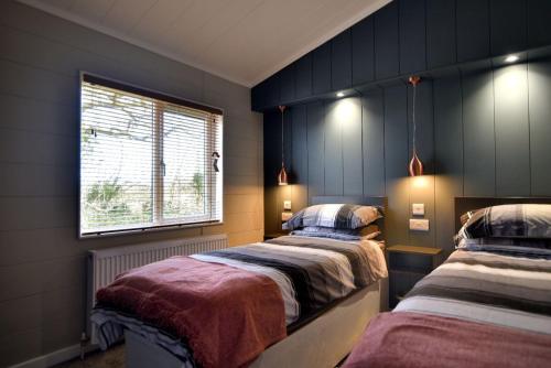 1 dormitorio con 2 camas y ventana en Hazelwood 4 Pinewood Retreat en Lyme Regis