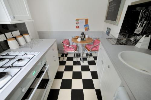 Una cocina con suelo a cuadros en blanco y negro. en Driftwood, en Lyme Regis