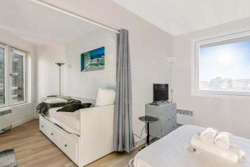 a white bedroom with a bed and a window at Nice studio with seaview in Deauville port - Welkeys in Deauville