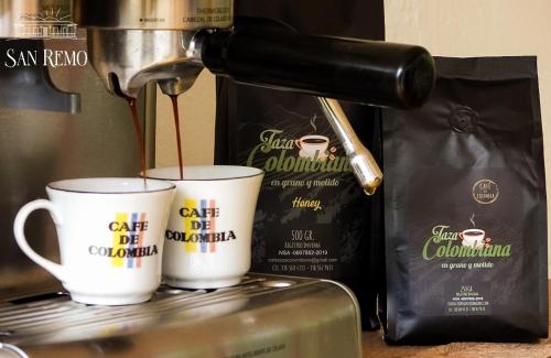 a coffee maker pouring coffee into two cups at Hotel Rural SAN REMO in Santa Rosa de Cabal