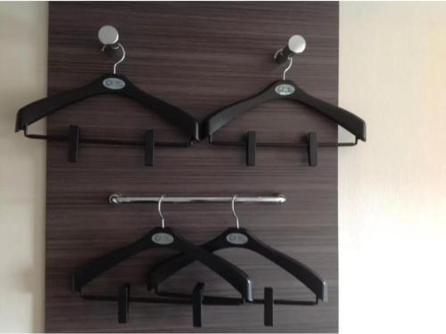 a wooden closet with three black hangers at R&B HOTEL HACHIOJI - Vacation STAY 38827v in Hachioji