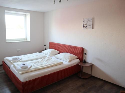 HeedeにあるWohnung "Amsterdam"の赤いヘッドボード付きの客室の小さなベッド1台分です。