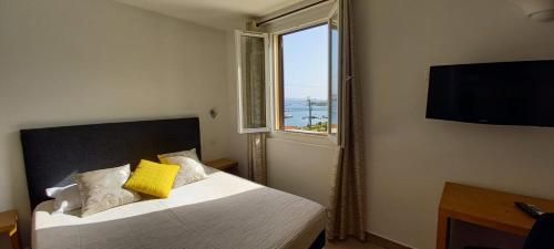 - une chambre avec un lit, une fenêtre et une télévision dans l'établissement Hôtel du Golfe, à Bonifacio
