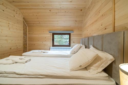 two beds in a wooden room with a window at Brvnara Ljubomir, planina Tara, Kaludjerske Bare in Kaludjerske Bare