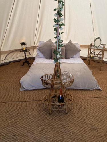 Egmanton的住宿－Southfields Bell Tent.，一间设有一张床和一张桌子及一瓶葡萄酒的客房