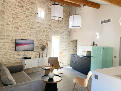 eine Küche und ein Wohnzimmer mit einer Steinmauer in der Unterkunft La Maison Favier in Saint-Rémy-de-Provence