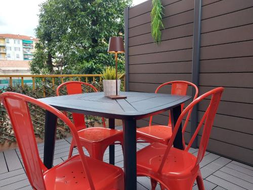 een zwarte tafel en rode stoelen op een patio bij PETITE MAISON ELEGANTE MONOLOCALE CON TERRAZZA in Chiavari