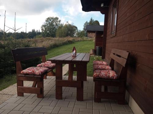 a wooden table and two chairs with a cat sitting on it at Chata Drevenica Orava in Oravská Lesná