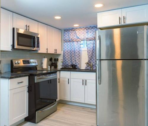 a kitchen with white cabinets and a stainless steel refrigerator at Spring Poconos Getaway! 2bd Cabin in Henryville