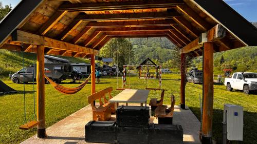 a wooden pavilion with a picnic table and a playground at Tara Place - Camp Rabrenovic in Mojkovac