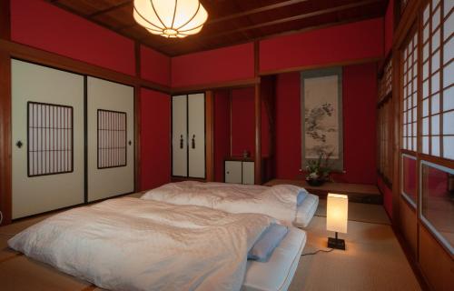 金沢市にあるWABI - Vacation STAY 52963vの赤い壁のベッドルーム1室、ベッド1台(ランプ付)