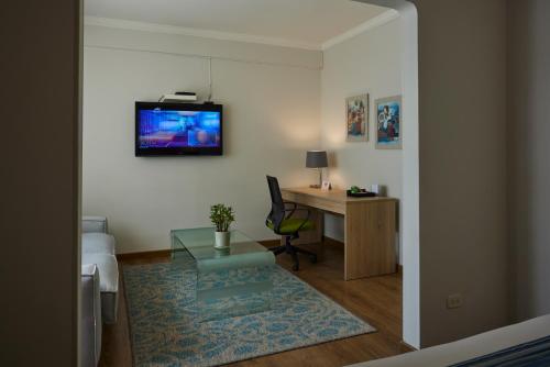 Zimmer mit einem Schreibtisch und einem TV an der Wand in der Unterkunft Hotel Saint Simon in Bogotá