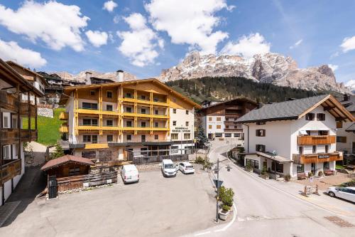 a street in a mountain town with cars parked at Residence Bosco Verde in San Cassiano