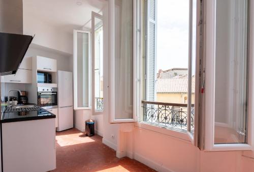 Il comprend une cuisine avec une grande fenêtre et un balcon. dans l'établissement appart cosy près gare, vieux port, MARSEILLE by Sam, à Marseille