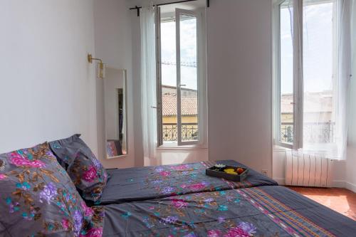 una camera da letto con un letto con un piumone colorato e finestre di appart cosy près gare, vieux port, MARSEILLE by Sam a Marsiglia