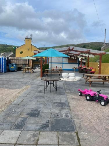 a patio with tables and benches and a blue umbrella at Danny's Bar & accommodation Broadford county Clare in Broadford