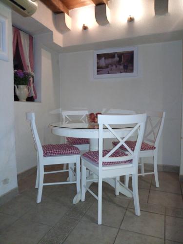 a dining room with a white table and chairs at Stone house Castellum in Kaštela