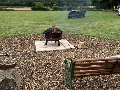 a grill in a yard with a tractor in a field at Southfields Bell Tent. in Egmanton