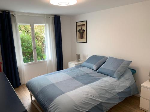Un dormitorio con una cama con almohadas azules y una ventana en L'echappée briarde, en Marles-en-Brie
