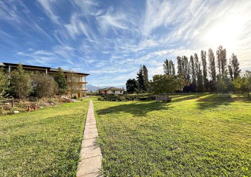 a path in a field with a house and trees at Hotel El Almendro in Paine