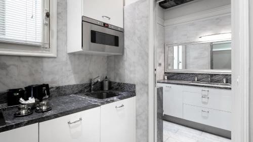 une cuisine avec des armoires blanches, un évier et un micro-ondes dans l'établissement The Paris Guest, à Paris