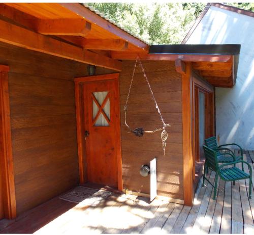 un porche de una cabaña con 2 sillas y una puerta a Cabana en el bosque en San Carlos de Bariloche