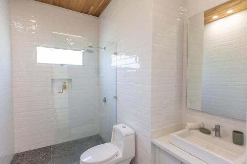 a white bathroom with a toilet and a sink at Villa Venus in Santa Teresa Beach