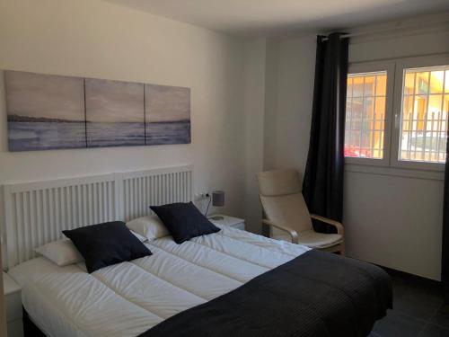a bedroom with two beds and a chair and a window at La Casita in Málaga