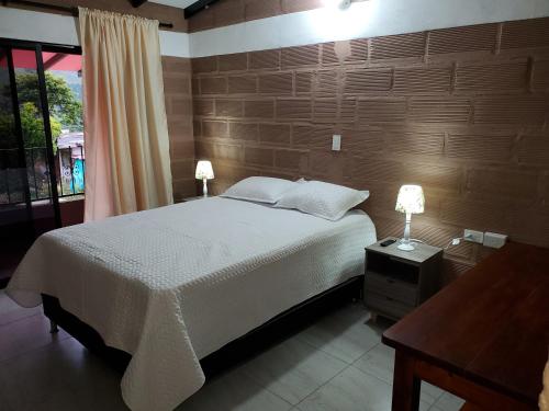 ein Schlafzimmer mit einem Bett und einem Tisch mit zwei Lampen in der Unterkunft CASA FINCA RANCHO APPALOOSA Vereda TIERRA LINDA Finca # 3 in Urrao