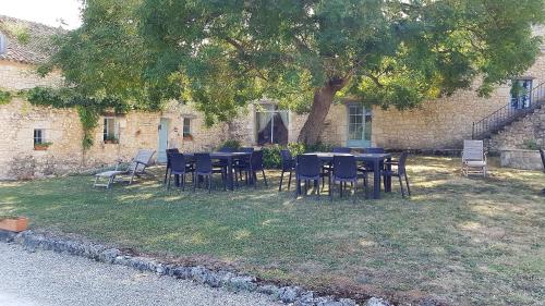 eine Gruppe von Tischen und Stühlen unter einem Baum in der Unterkunft Chambre d'hôte La Pierre in Conne-de-Labarde