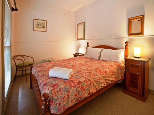 a bedroom with a bed and a table and a chair at Noonameena Cottage in Halls Gap