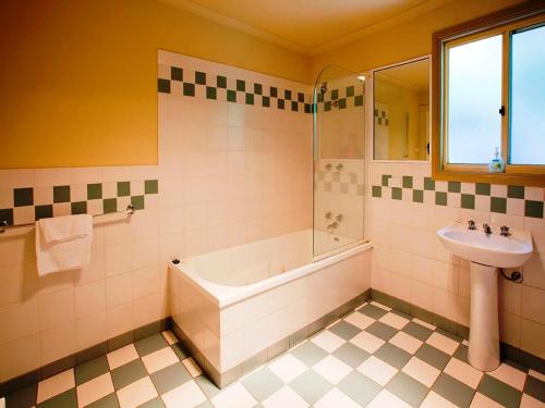 ein Badezimmer mit einer Badewanne und einem Waschbecken in der Unterkunft Noonameena Cottage in Halls Gap
