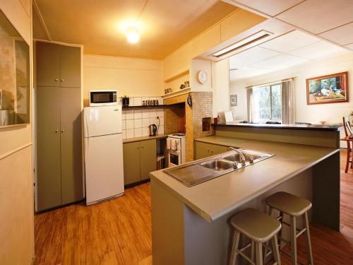 a kitchen with a sink and a white refrigerator at Noonameena Cottage in Halls Gap