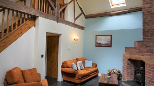 a living room with two chairs and a fireplace at Sheep Dip Cottage - 5* Cyfie Farm, with log burner and private hot tub in Llanfyllin