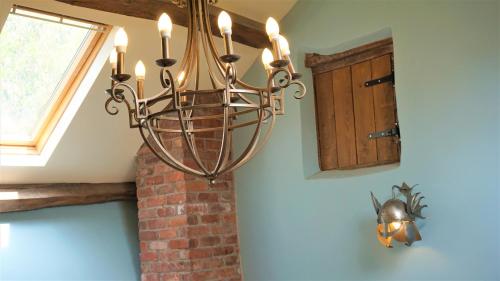 a chandelier hanging in a room with a brick wall at Sheep Dip Cottage - 5* Cyfie Farm, with log burner and private hot tub in Llanfyllin