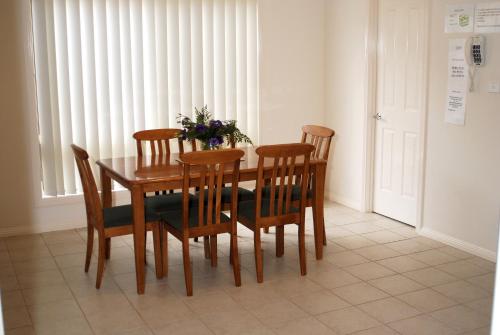 a dining room table and four chairs with flowers on it at Melton Motor Inn and Apartments in Melton
