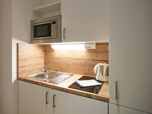 a small kitchen with a sink and a microwave at Messe München Smartapart in Munich