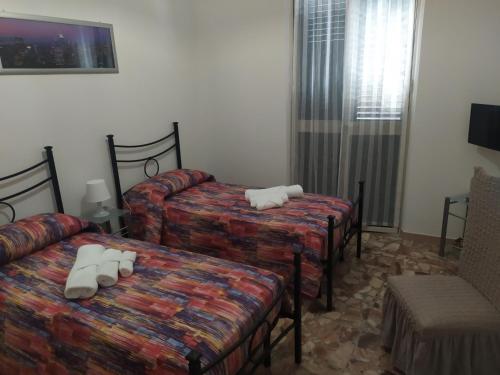 a hotel room with three beds and a chair at La casa di Ornella in Avola